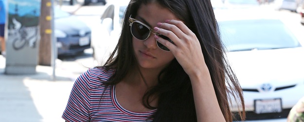Selena Gomez walking into a sound studio holding a book in Los Angeles