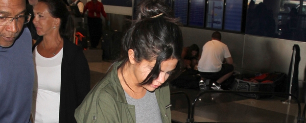 Selena Gomez goes undercover at LAX in a midriff and high-waisted paints as she catches a flight out of Los Angeles.